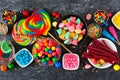 Colorful sweet candy buffet table scene, above view over dark stone