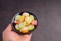 Colorful sweet jelly candy on a black plate on a palm with a dark brown background. Jelly circle breaded in sugar. Top view Royalty Free Stock Photo