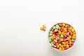 Colorful sweet popcorn from shop in a white bowl on a white table. Delicious treat. Top view. Royalty Free Stock Photo