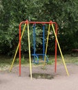 Colorful swings on the playground near green trees