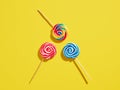 Colorful swirl round candy lollipops on yellow background