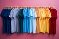 colorful t - shirts hanging on clothes rack on pink wall Royalty Free Stock Photo