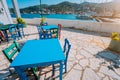 Colorful table and chairs at the sunny terrace. Traditional countryside tavern by the sea. Greek fishing village at hot Royalty Free Stock Photo