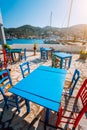 Colorful table and chairs in a typical tavern by the sea. Greek fishing village at hot summer day Royalty Free Stock Photo