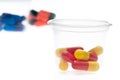 Colorful tablets, capsules in a cup