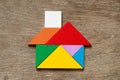 Colorful tangram puzzle in home shape on wood background