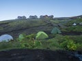 Colorful tents and Botnar mountain hut at Iceland on Laugavegur hiking trail, green valley in volcanic landscape among