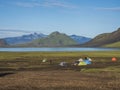 Colorful tents at camping site on blue Alftavatn lake with green hills and glacier in the otherwordly beautiful