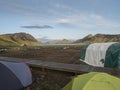 Colorful tents at camping site on blue Alftavatn lake with green hills and glacier in the otherwordly beautiful