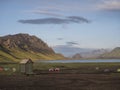 Colorful tents at camping site on blue Alftavatn lake with green hills and glacier in the otherwordly beautiful