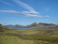 Colorful tents at camping site on blue Alftavatn lake with green hills and glacier in the otherwordly beautiful