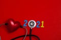 Colorful on text 2021 banner for health care and Red heart love medical concept. black stethoscope,on table red background