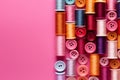 Colorful thread spools and buttons on pink background, top view Royalty Free Stock Photo