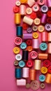 Colorful thread spools and buttons on pink background, top view Royalty Free Stock Photo