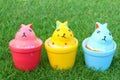 Colorful three rabbits in ceramic cups on grass background Royalty Free Stock Photo