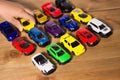 Colorful toy cars side view on a wooden floor background with small child hand holding the toy Royalty Free Stock Photo