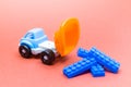 Colorful toy truck on a pink background and with constructor blocks