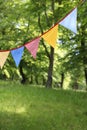 Colorful triangular bunting flags hanging among trees. Summer garden party. Outdoor birthday or wedding decoration Royalty Free Stock Photo