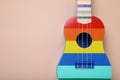 Colorful ukulele on beige background, top view and space for text. String musical instrument