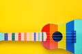 Colorful ukulele on yellow background, top view with space for text. String musical instrument