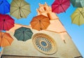 Colorful umbrellas against gothic cathedral and blue sky.