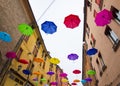 Colorful umbrellas floating in the sky above the ancient UNESCO listed town centre of Ferrara, Italy.