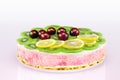Colorful unbaked homemade fruit cake with cream and sweet cherries
