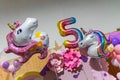 Colorful unicorn-shaped balloons and a \'5\' balloon.