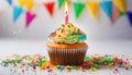A colorful vanilla cupcake sitting on the counter with a lit candle, sprinkles and a pennant banner for a birthday Royalty Free Stock Photo