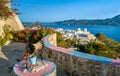 Colorful view on traditional Greek town by sea from decorated terrace with rich red cranesbills. White Orthodox Greek Royalty Free Stock Photo