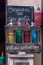 Colorful vintage soda bottles on display in a rustic wooden crate at a wine store with a sign in Catalan that reads Old town