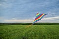 Colorful vivid rainbow kite flying on green field meadow and blue cloudy sky in summer. Family leisure activity. Happy springtime Royalty Free Stock Photo