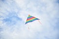 Colorful vivid rainbow kite flying on light blue cloudy sky in summer. Family leisure activity. Happy springtime lifestyle. Child Royalty Free Stock Photo