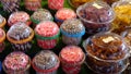 Colorful wafer rolls packed in transparent containers, displayed neatly next to other snacks
