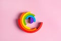 Colorful Waldorf wooden rainbow in a montessori teaching pedagogy on pink background, kid play concept