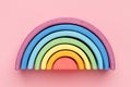 Colorful Waldorf wooden rainbow in a montessori teaching pedagogy on pink background