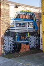 A colorful wall mural of a blue Ford Monster truck on the side of a red brick buildings in Little Five Points