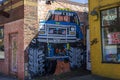 A colorful wall mural of a blue Ford Monster truck on the side of a red brick buildings in Little Five Points