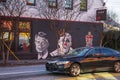 a colorful wall mural with Colin Kaepernick kneeling, Jimmy Carter, and a clown on a black brick wall in Atlanta Georgia