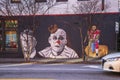 a colorful wall mural with Colin Kaepernick kneeling, Jimmy Carter, and a clown on a black brick wall in Atlanta Georgia