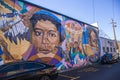 A colorful wall mural with people in Little Five Points surrounded by parked cars with a gorgeous clear blue sky in Atlanta