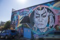 A colorful wall mural of people on the side of a brick building in Little Five Points surrounded by parked cars