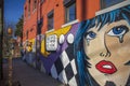 a colorful wall mural with three women crying over the traffic on the side of a red brick buildings with cars and trucks driving Royalty Free Stock Photo