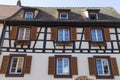 Colorful wall of old half-timbered house with multiple windows and wooden shutters, close-up