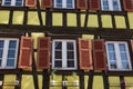 Colorful wall of old half-timbered house with multiple windows and wooden shutters, close-up