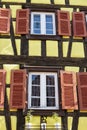 Colorful wall of old half-timbered house with multiple windows and wooden shutters, close-up