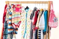 Dressing closet with kids clothes arranged on hangers.