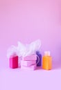 Colorful washcloths, plastic travel bottles and bars of soap on a soft pink background. Accessories for body care and hygiene