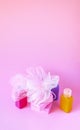 Colorful washcloths, plastic travel bottles and bars of soap on a soft pink background. Accessories for body care and hygiene