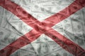 Colorful waving alabama state flag on a american dollar money background